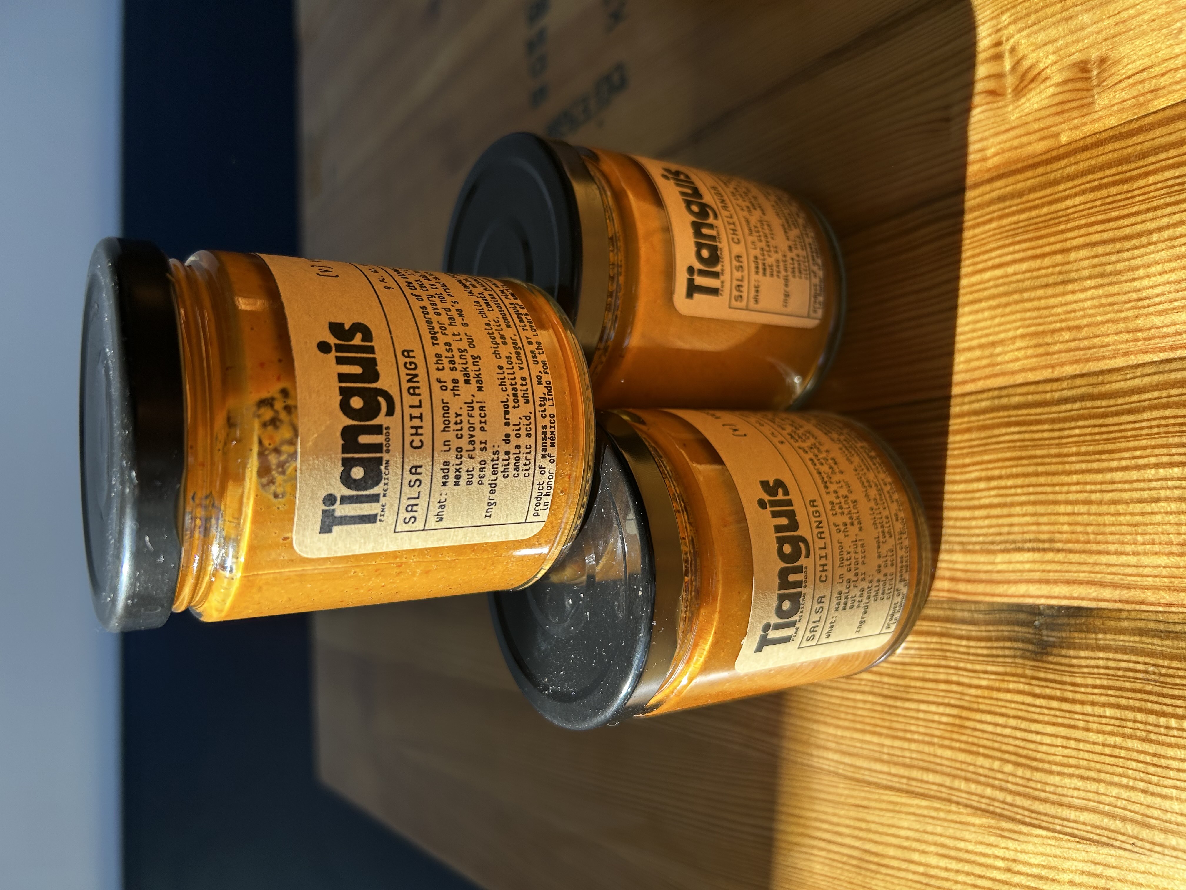 three jars of mustard sitting on a wooden table